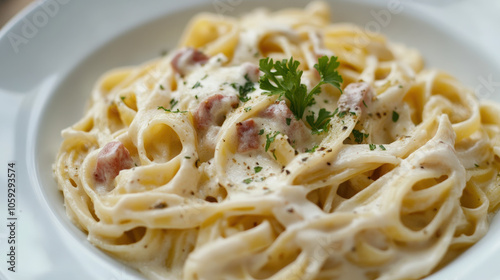 A bowl of pasta with a creamy white sauce and parsley on top