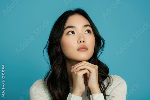 attractive asian woman thinking isolated on blue background