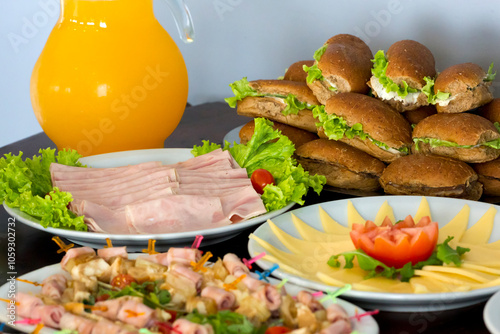 Catering with toamte, ham, salami, olives, orange juice, sandwiches on white bread and bran bread, cheese, vegetables, fruits, etc.