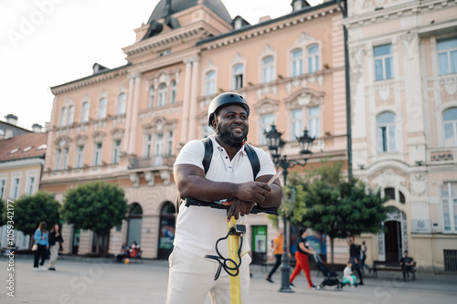 Tourist wearing helmet leaning on electric scooter in city center