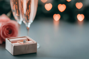 An engagement ring and two glasses with rose sparkling wine. Proposal with diamond ring. Valentine's day, romantic wedding invitation, love greeting card. Dating, falling in love, wedding celebration