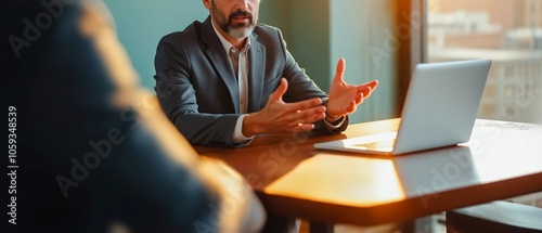 Business Meeting - Collaborative Discussion , A professional man in a suit gesticulates during a conversation at a desk. He sits across from an unseen individual, engaged in a focused discussion. photo