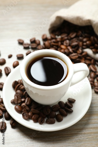 Cup of coffee and coffee beans on wooden background