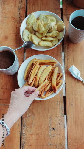 Candid scene of enjoying pritong saging or fried banana and sweet potatoes or kamote paired with coffee for a traditional Filipino afternoon snack or merienda photo