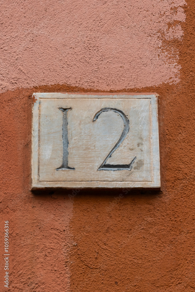 Carved number twelve door number on plaster wall background Carved number twelve door number on plaster wall background