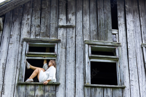 Modern Elegance in a Historic Window: A Woman Posing in an Old House, Surrounded by Memories