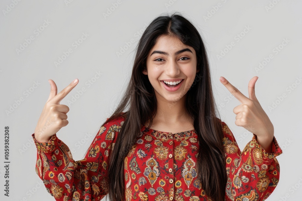 Cheerful Pakistani girl pointing to copy space in studio portrait