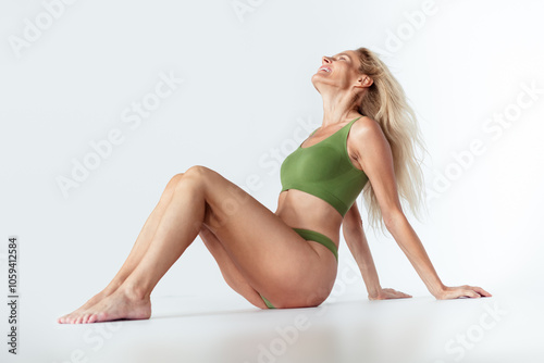 Full body photo of attractive mature blonde woman sit floor relax wear khaki fashion lingerie isolated white background no filter photo