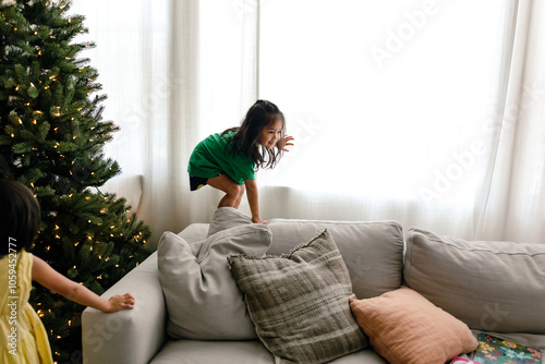 Sisters play by Christmas tree photo