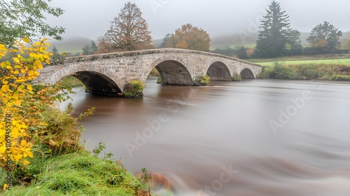 Fogbound Bridge: An old stone bridge spans a fog-filled river, its arches disappearing into the haze.  photo