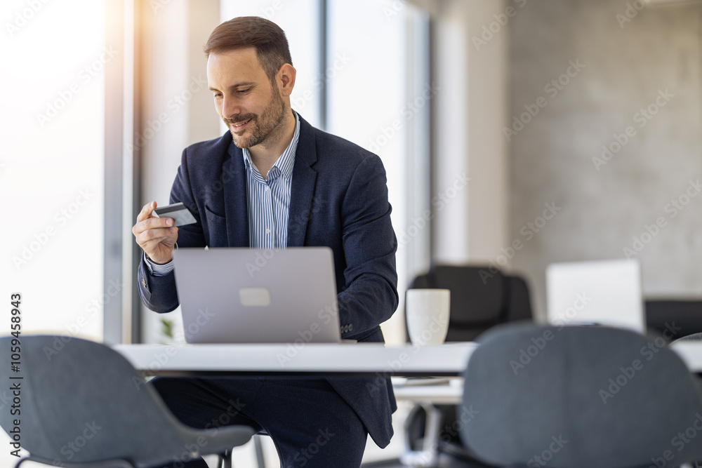 Confident Businessman Using Laptop and Credit Card at Office Confident Businessman Using Laptop and Credit Card at Office