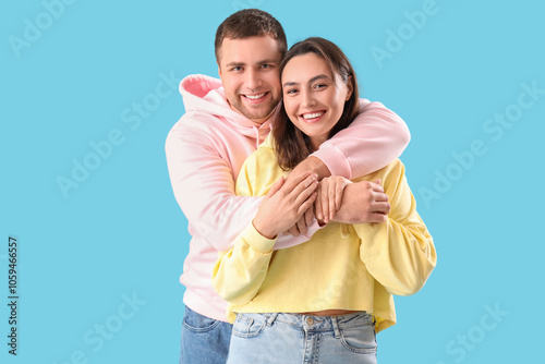 Happy young couple hugging on blue background
