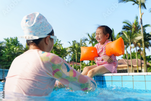 little girl feel cold sitting by the swimming pool photo