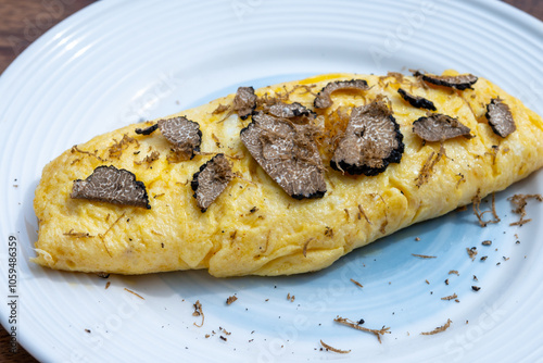 French omelette with mushrooms, fresh farmers eggs and black summer truffle mushroom in pieces for making truffle dishes with tasty aroma