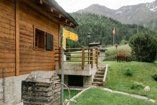 Swiss chalet with alps in background, and hike signage in front photo