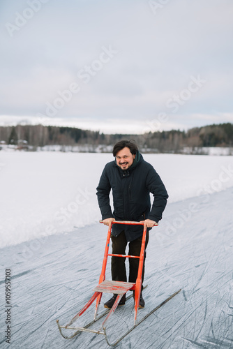 Man in dark jacket enjoying ride on red kick sled. photo