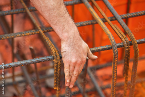 Crafting strength in construction: a steel fixer hand shaping steel reinforcement at a bustling construction site photo