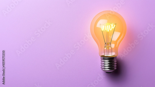 Lit incandescent light bulb against purple background, showcasing energy and innovation symbol.