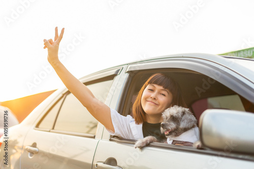 Young asian woman in casual outfit of cheerful with dog looking out of car window. Young female going on a road trip with her pet and smiling owner having good time together. Vacation with pet concept #1059591736