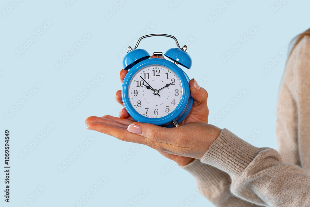 Ταπετσαρία A woman's hand holds a vintage blue alarm clock, symbolizing the importance of t