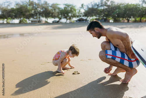 Father and daughter looking at burrowing crab on the beach photo