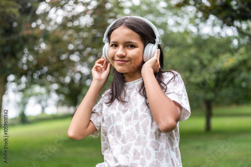 Venezuelan girl enjoying music in the park wearing headphones photo