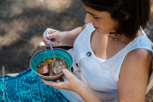 Woman enjoying a bowl of homemade lentil stew on a colorful blue plate photo