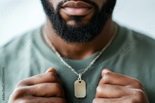 A bearded man holds a dog tag necklace around his neck, showcasing a simple yet meaningful accessory that adds character and depth to his personal style. photo