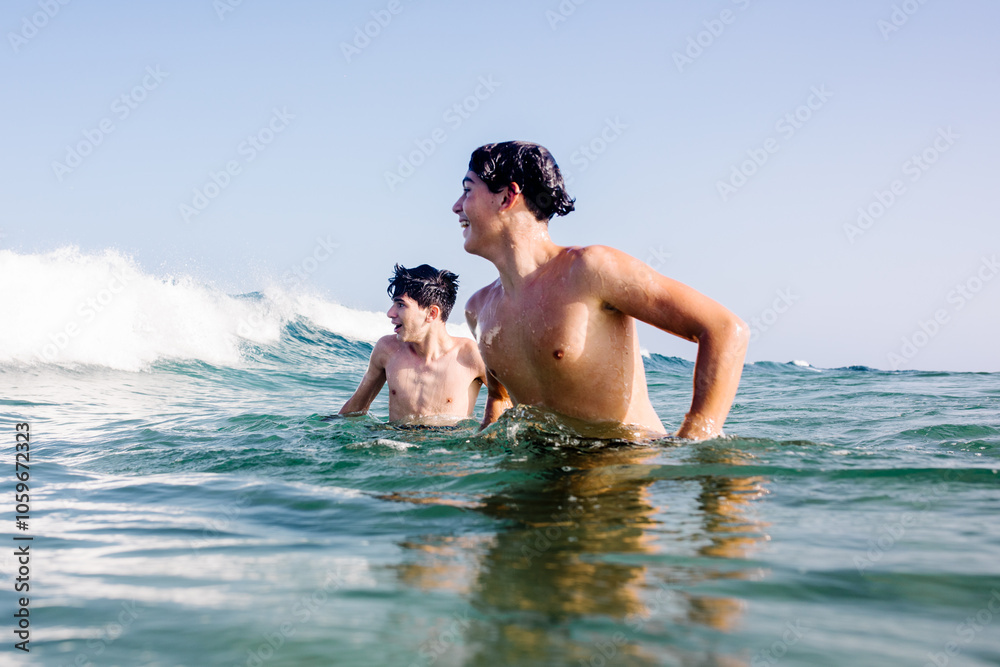Teenage brothers have fun with the waves at Papagayo Beach, Lanzarote Teenage brothers have fun with the waves at Papagayo Beach, Lanzarote