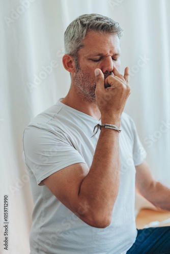 A man sitting in lotus position, practicing alternate nostril breathing exercises during a meditation session photo