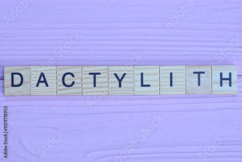 word dactylith from gray wooden small letters with black font on an pink background photo