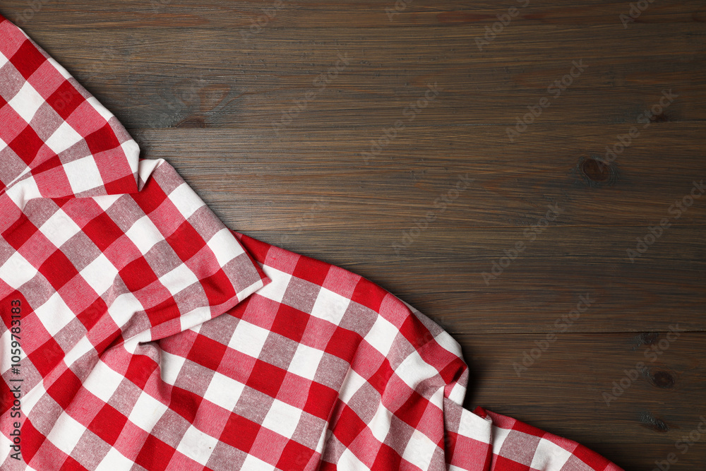 Obraz premium Crumpled tablecloth with checkered pattern on wooden table, top view. Space for text