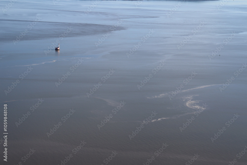 The stream and the current of the water on a large river with a little lighthouse. Water background and blue. Vast river in Quebec and the St-Laurent river in Charlevoix. The surface of the water. The stream and the current of the water on a large river with a little lighthouse. Water background and blue. Vast river in Quebec and the St-Laurent river in Charlevoix. The surface of the water.