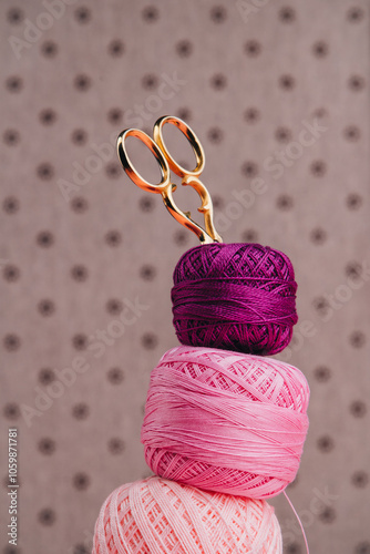 A pile of colorful yarn with vintage scissors stuck in it and lace ribbon perfect for sewing, knitting and other creative hobbies, vertical photo. photo