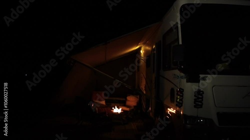 Campfire on side of Rv motorhome with chairs under awning