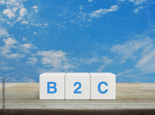 B2C acronym on white block cubes on wooden table over blue sky with white clouds, Business to customer marketing and strategy concept photo