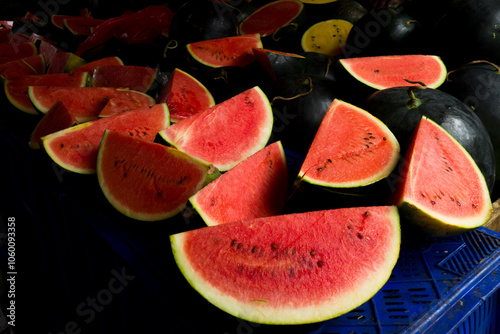 des tranches de pasteques rouge vif avec l'ecorce verte sur l'etal d'un marchand sur un marché de rue