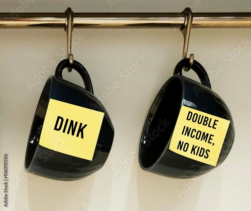 Two coffee cups with stick note written DINK acronym stands for Double Income, No Kids - referring to couples who are voluntarily childless