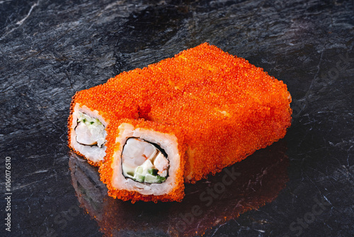 Japanese rolls, California sushi with tobiko caviar, crab meat and cream cheese and cucumber on a black marble background. photo