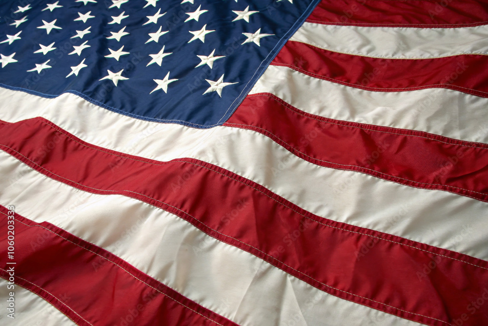 Obraz premium Detailed image of the American flag waving gracefully in sunlight, showcasing stars and stripes. Represents patriotism, national pride, and American culture.
