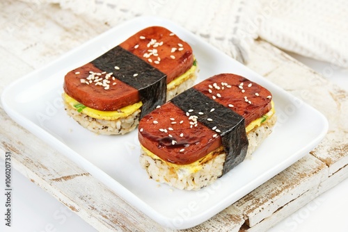 Classic Hawaiian spam musubi, made with grilled spam, seasoned rice, and wrapped with nori seaweed. A delightful fusion snack that combines savory, salty, and umami flavors in each bite.