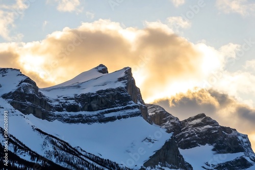 Picos de Montanha Cobertos de Neve ao Pôr do Sol com Nuvens Douradas photo