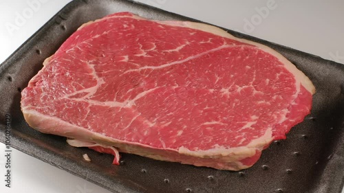 Beef steak in black plastic box tray.