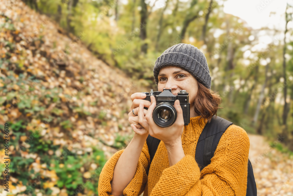 Young Caucasian woman photographer with analog photo camera enjoying autumn nature and weather