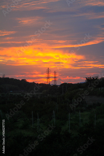 A dramatic sunset sky with colourful glowing clouds and a silhouetted landscape below photo