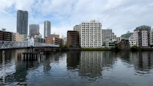 Tokyo's Harumi district cityscape reflected in calm river waters under a cloudy sky photo