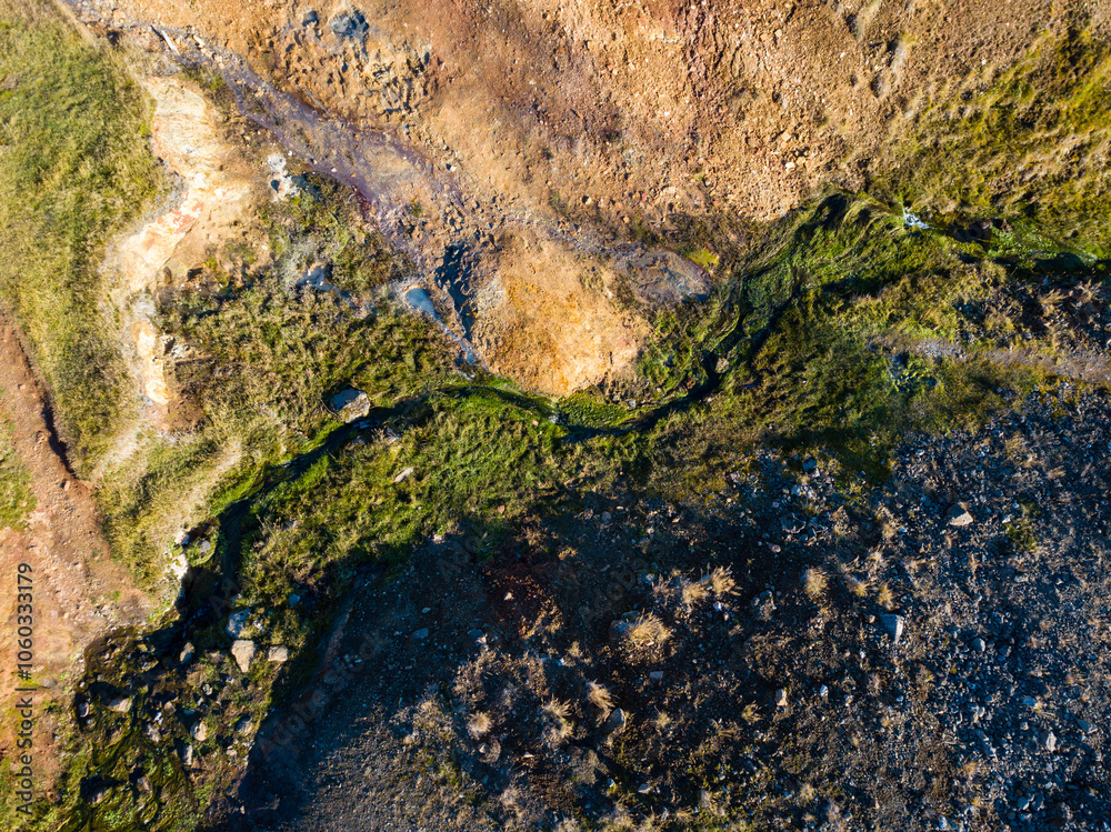 Aerial perspective of a geothermal river meandering through a colorful terrain, highlighting the unspoiled allure of iceland's natural environment Aerial perspective of a geothermal river meandering through a colorful terrain, highlighting the unspoiled allure of iceland's natural environment