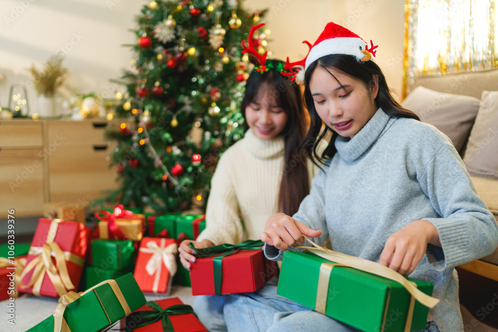 Two friends in festive attire sitting by a beautifully decorated Christmas tree with a variety of wrapped gifts around them, sharing a joyful holiday moment together Two friends in festive attire sitting by a beautifully decorated Christmas tree with a variety of wrapped gifts around them, sharing a joyful holiday moment together