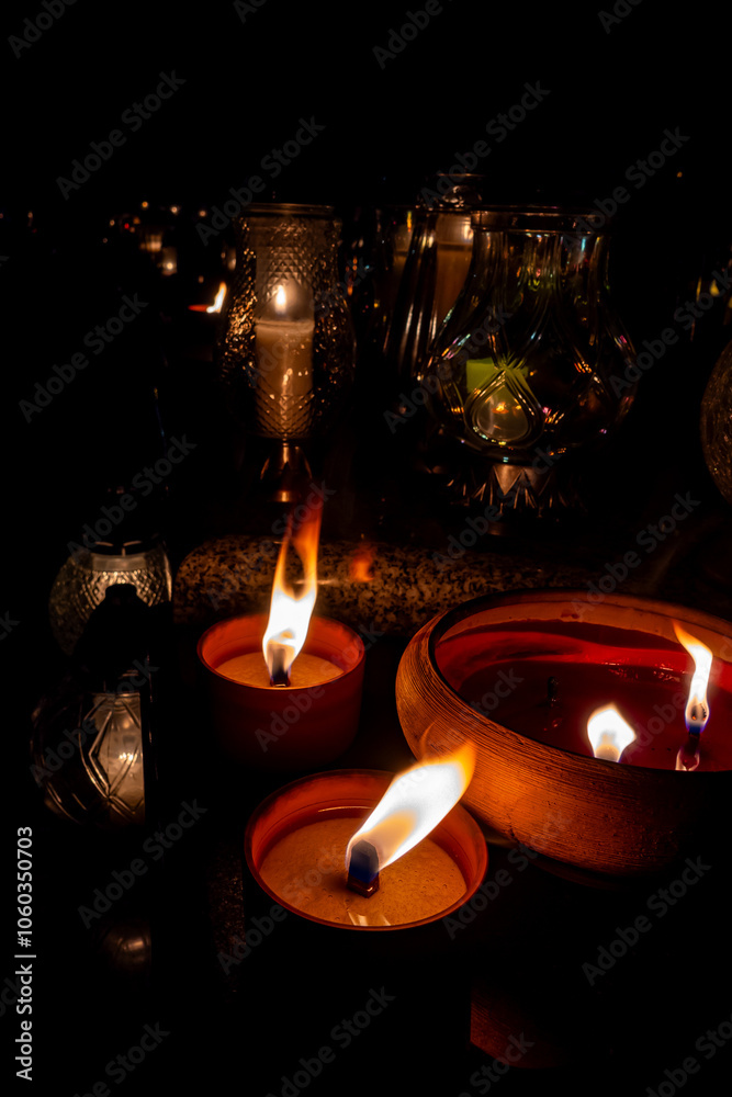 Flames on clay cemetery candles standing on tombstones. The shot was taken in the evening of All Saints' Day, November 1.