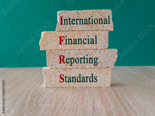 IFRS symbol. Concept words IFRS International Financial Reporting Standards on brick blocks. Beautiful green background, wooden table. Business concept.